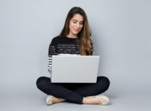 Kobieta siedzi z laptopem na kolanach